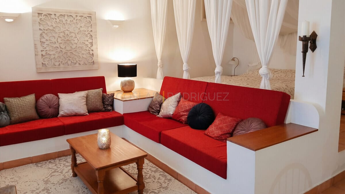 Geräumiger Wohnbereich mit roten Sofas, Wanddeko und Himmelbett.