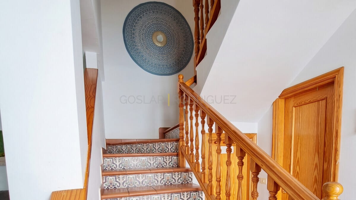 Verzierte geflieste Treppe mit Holzgeländer und Mandala-Wandkunst.