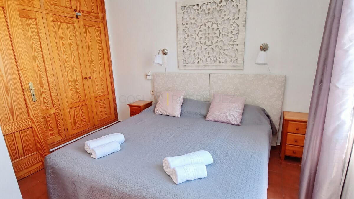 Gemütliches Schlafzimmer mit großem Holzschrank, weicher Bettwäsche und Wanddeko.