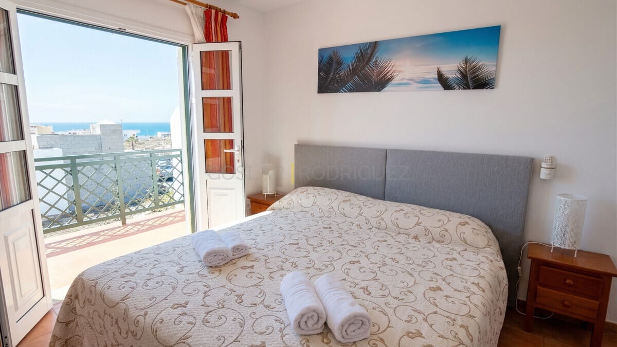 Helles Schlafzimmer mit Bett, Balkonzugang und Meerblick in modernem Zuhause.