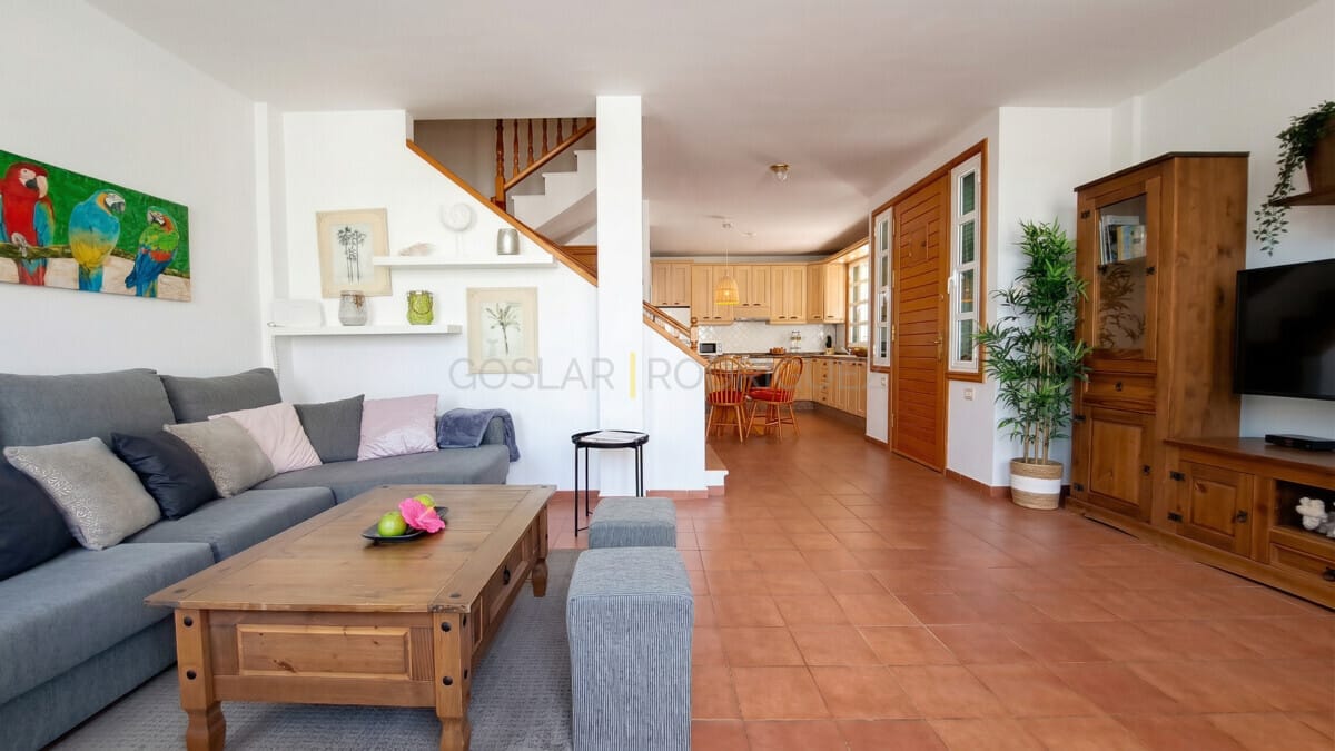 Geräumiger Wohnbereich mit Sofa, Holztisch und offener Küche, hell und einladend.