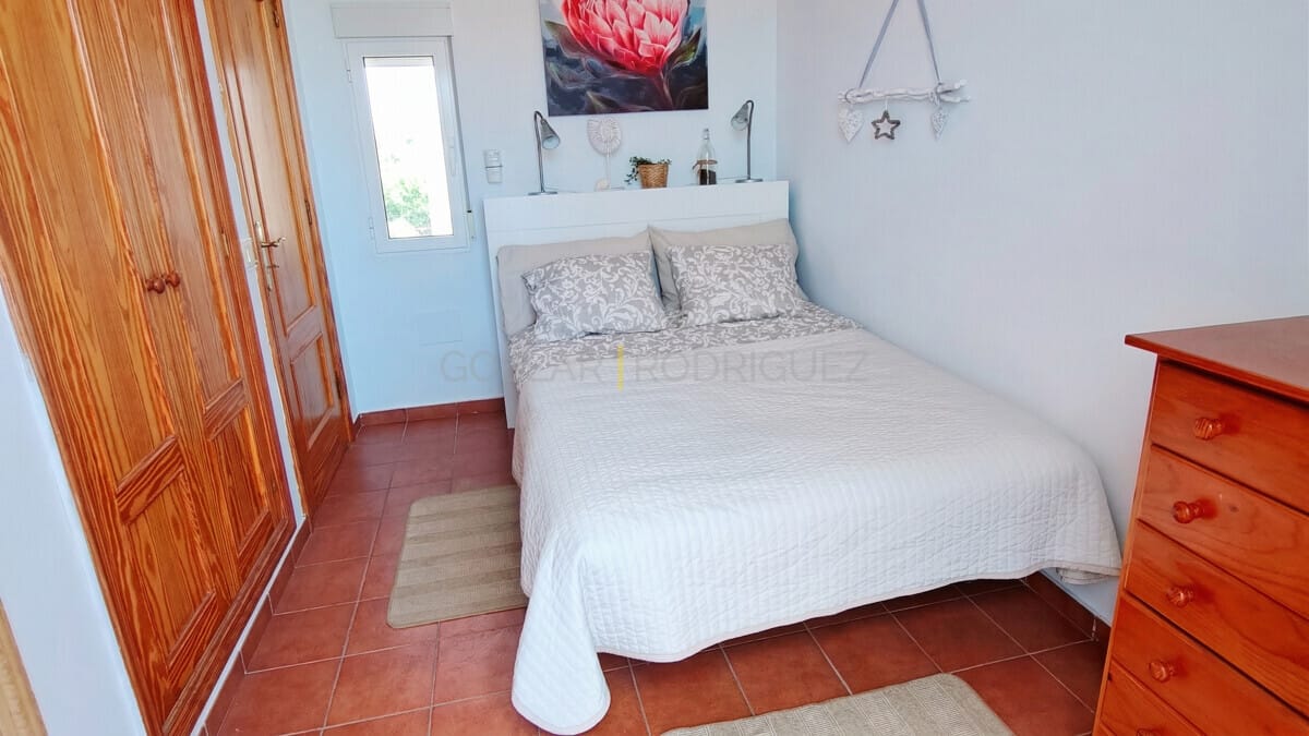 Ein gemütliches Schlafzimmer mit einem weißen Bett, einem Holzschrank und einer roten Kommode.