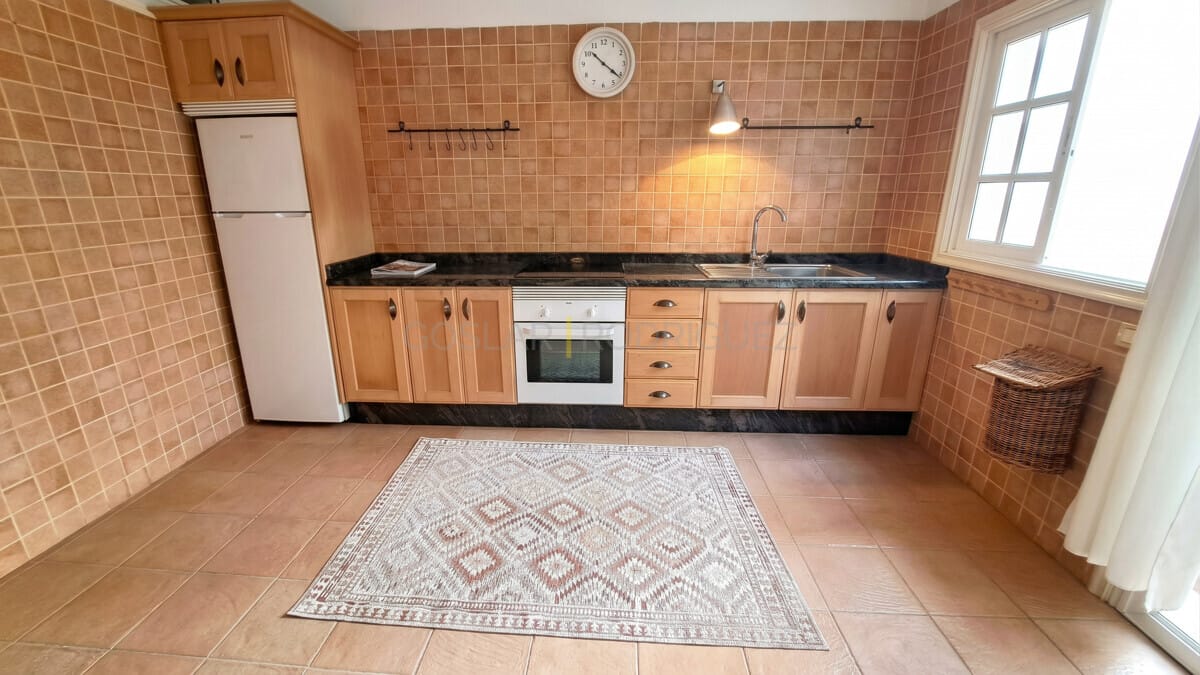 Helle Küche mit Holzschränken, Backofen und großem Fenster.