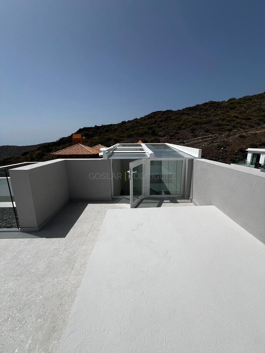 Dachterrasse einer Villa in Adeje, Teneriffa. Die Terrasse verfügt über eine Glasüberdachung und bietet einen Blick auf die umliegenden Berge.