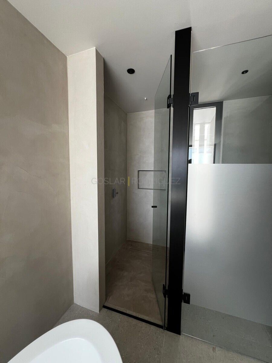 Modernes Badezimmer mit begehbarer Dusche in einer Villa in Adeje auf Teneriffa. Das Design zeichnet sich durch graue Fliesen und eine rahmenlose Glasduschtür aus.