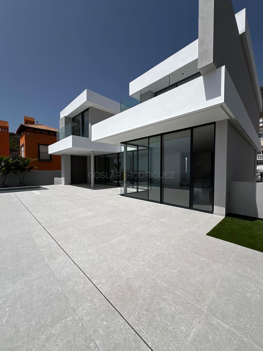 Außenansicht einer modernen Villa in Adeje im Süden von Teneriffa. Das luxuriöse Anwesen verfügt über große Glasfronten und eine weitläufige Terrasse.