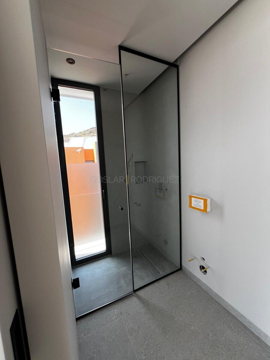 Modernes Badezimmer mit ebenerdiger Dusche in einer Villa in Adeje auf Teneriffa. Zu sehen ist eine Duschkabine aus Glas mit schwarzem Rahmen und eine teilweise Milchglaswand.