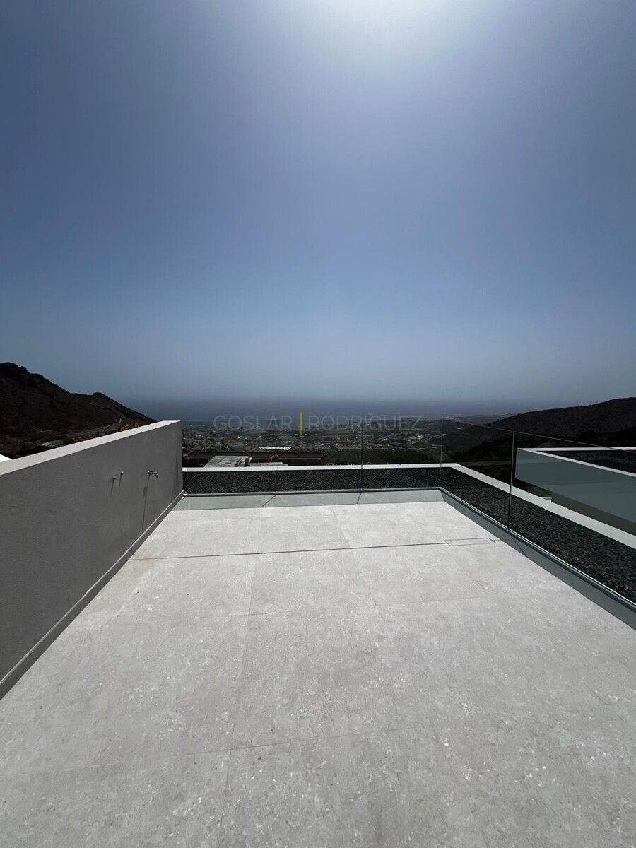 Aussicht von der Terrasse einer Villa in Adeje auf Süd-Teneriffa. Blick auf die Küste und die Landschaft. Die Terrasse hat eine moderne Gestaltung mit Glasgeländer und grauen Fliesen.