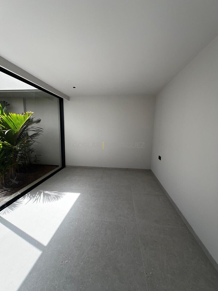 Helles, modernes Wohnzimmer mit großem Fenster und Blick auf tropische Pflanzen.