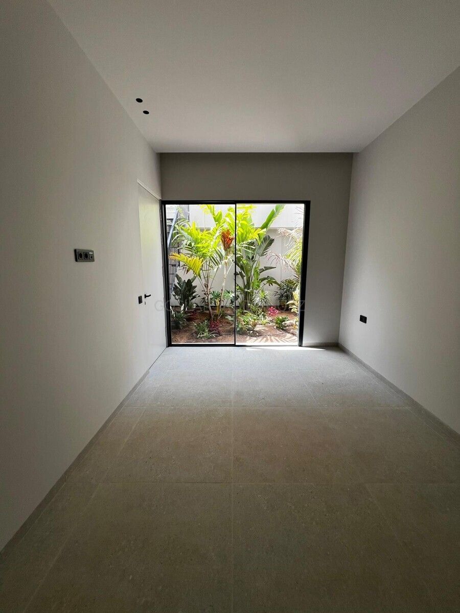 Innenansicht einer Villa in Adeje auf Teneriffa: Heller Raum mit Blick auf einen begrünten Innenhof. Die großen Glasfenster lassen viel Licht herein.