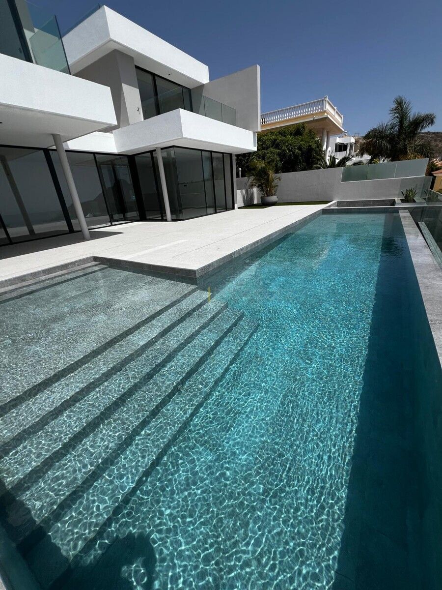 Swimmingpool einer modernen Villa in Adeje, Teneriffa. Die Terrasse ist mit hellgrauen Fliesen ausgelegt, und der Pool hat klares, blaues Wasser.
