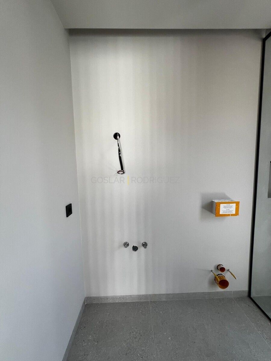 Badezimmer im Bau in einer Villa in Adeje, Teneriffa. Graue Bodenfliesen, weiße Wände mit vorinstallierten Wasseranschlüssen und einem Schalter.