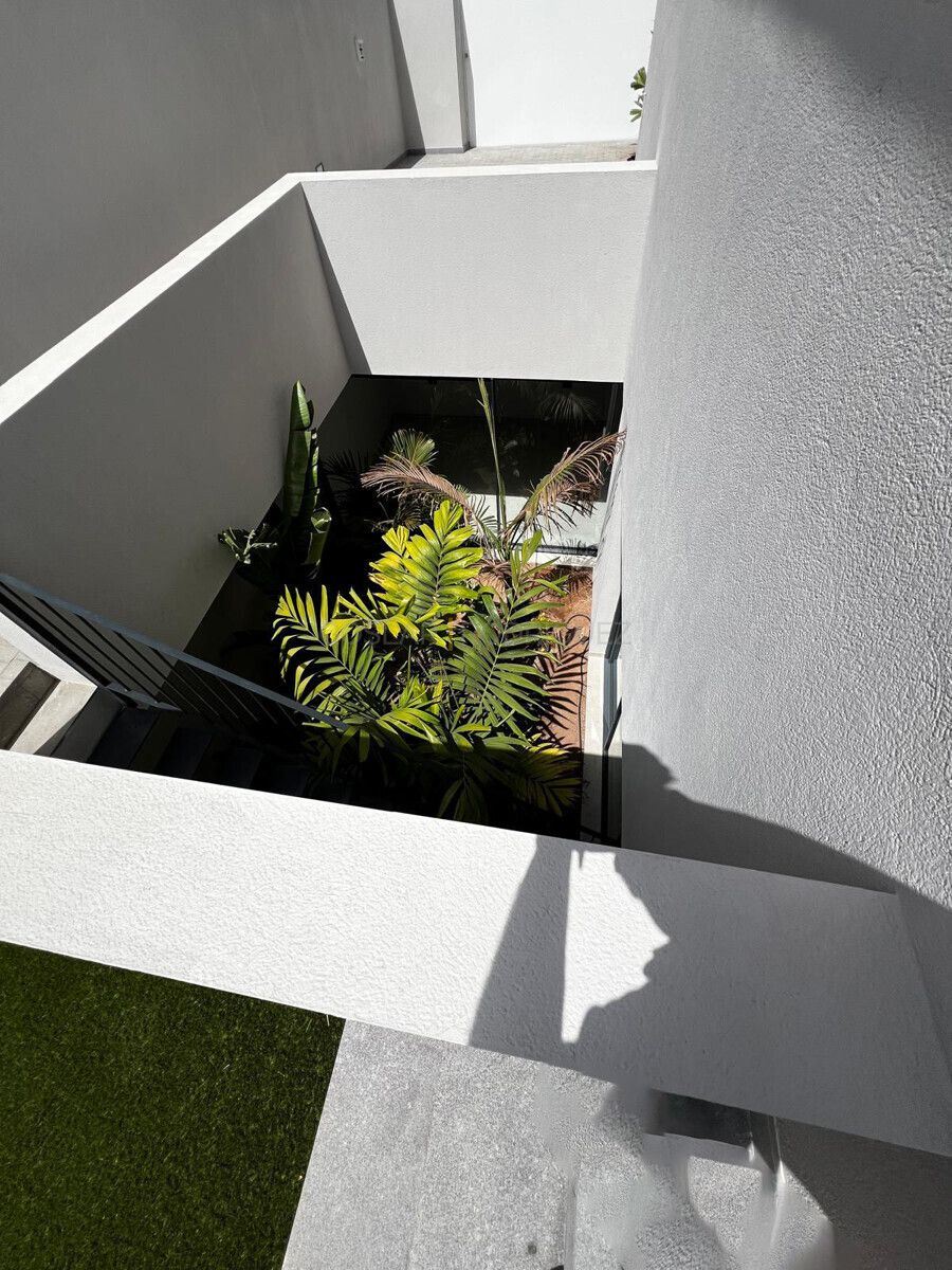 Innenhof einer modernen Villa in Adeje auf Teneriffa, fotografiert von oben. Verschiedene Pflanzen wachsen im Innenhof, der von weißen Wänden umgeben ist.