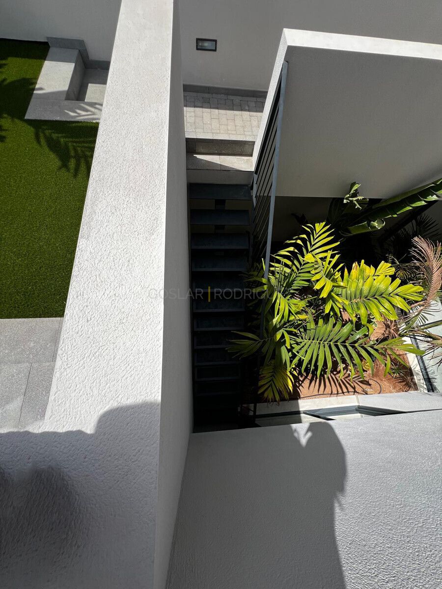 Aussenansicht einer modernen Villa in Adeje, Teneriffa. Blick von oben auf den Garten mit Kunstrasen, Treppe und tropischen Pflanzen.