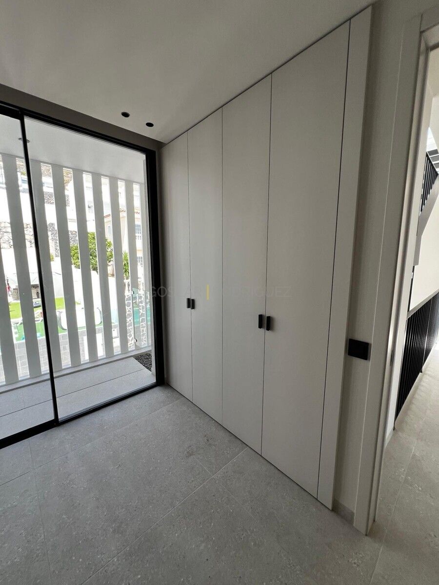 Helles Schlafzimmer in einer Villa in Adeje auf Teneriffa. Der Raum verfügt über einen Einbauschrank mit hellen Fronten und einen Zugang zu einem Balkon mit Jalousien.