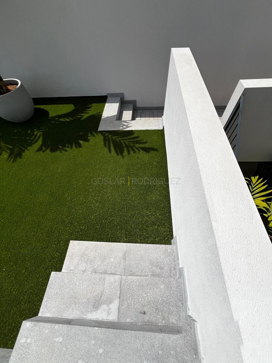 Detailansicht des Gartens einer Villa in Adeje auf Teneriffa. Der Garten verfügt über Rasen, Steintreppen und Schatten von Palmen.