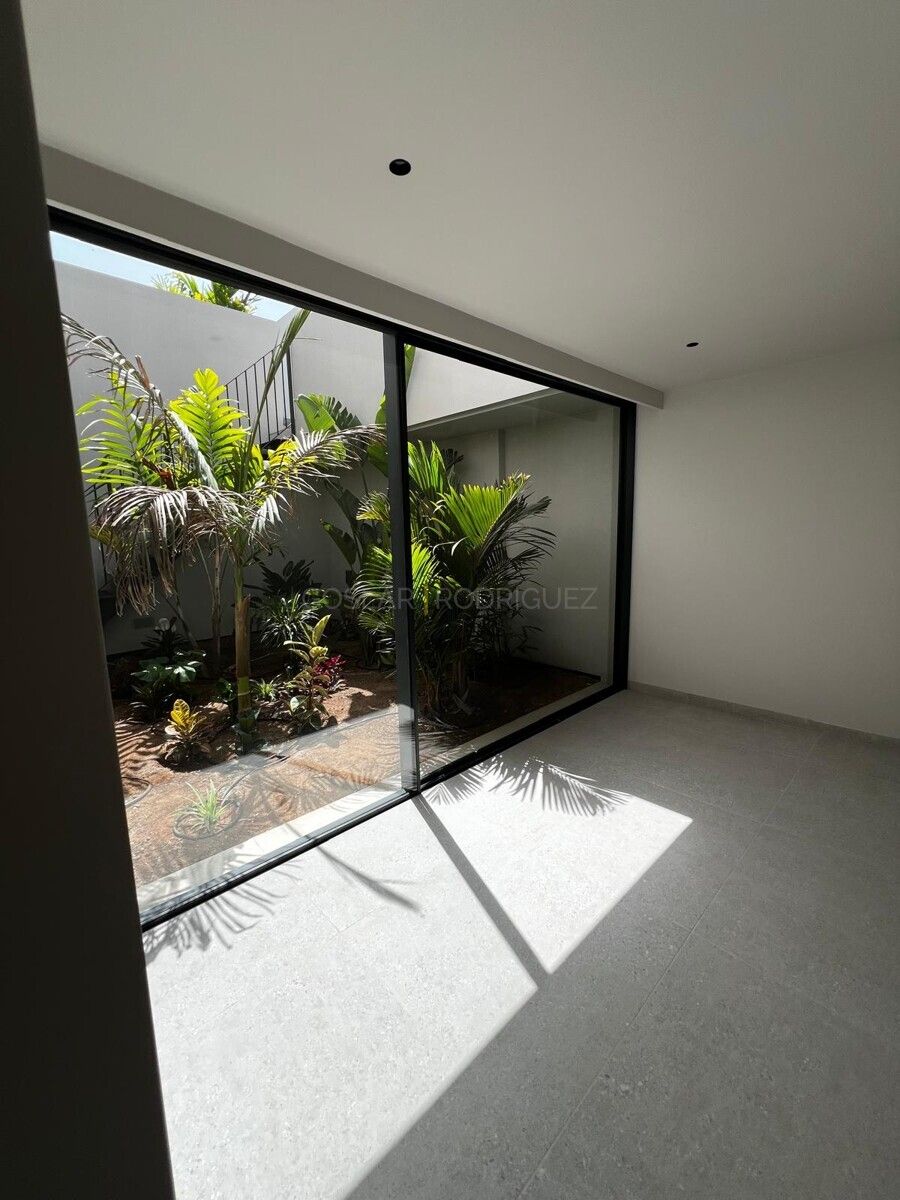 Heller Raum mit Blick auf einen begrünten Innenhof durch eine große Glasfront. Detailansicht einer Villa in Adeje im Süden von Teneriffa mit üppigem Gartenblick. Dieses Foto zeigt die helle und moderne Architektur.