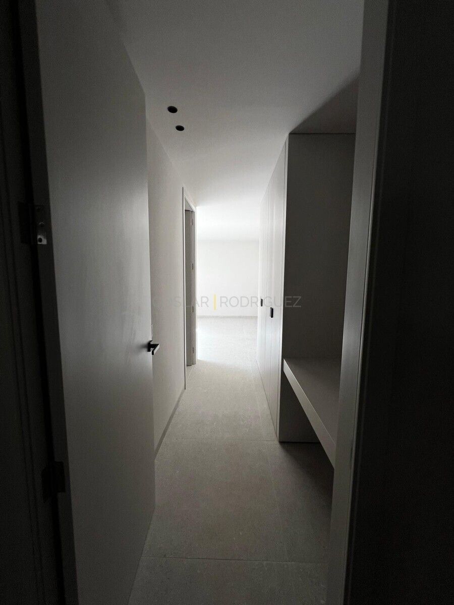 Heller Flur in einer Villa in Adeje, Teneriffa. Helle Wände, Fliesenboden und Einbauschränke sind sichtbar.