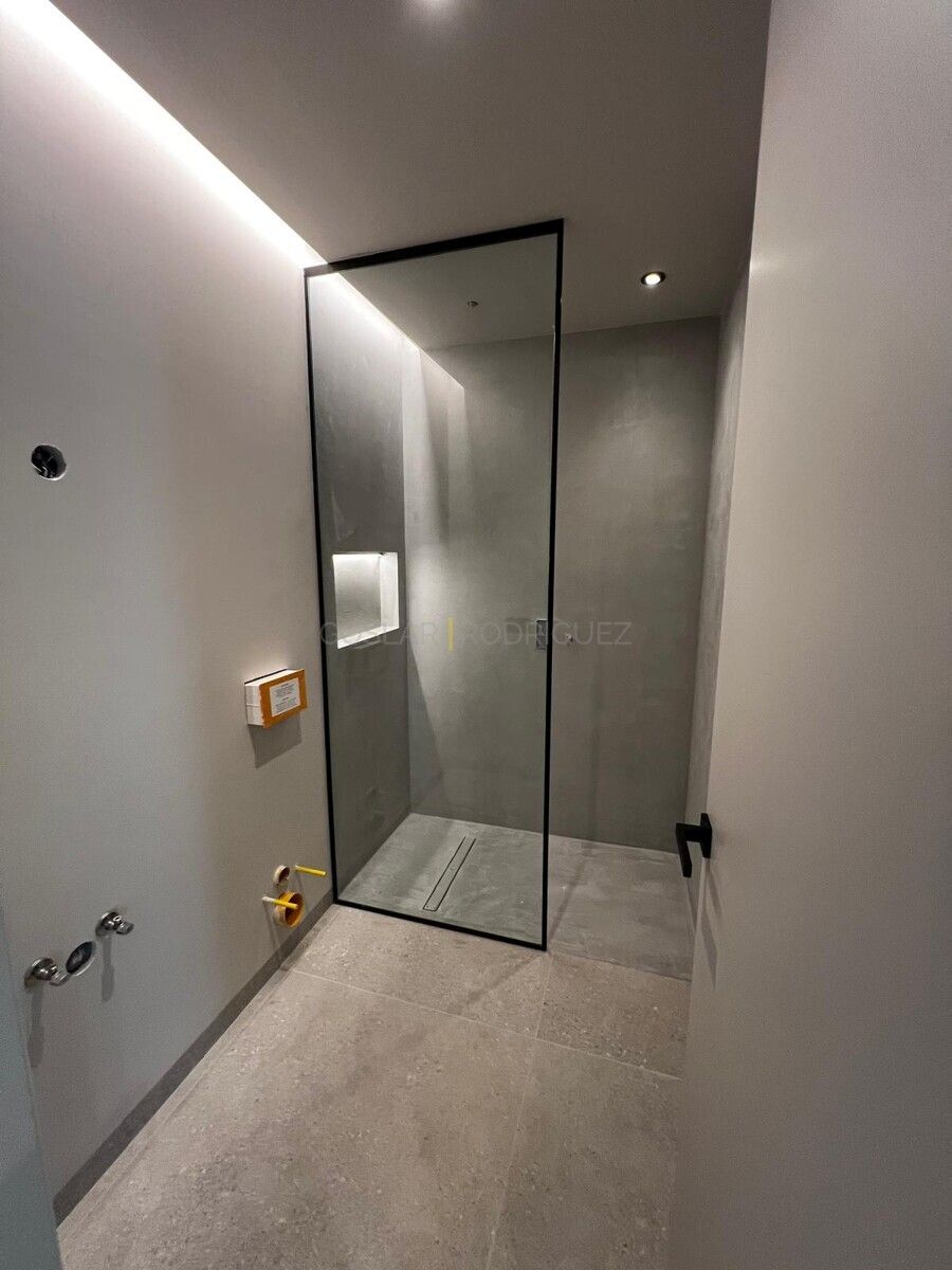 Badezimmer mit moderner Dusche und Blick nach draußen in einer Villa in Adeje auf Teneriffa. Die Dusche verfügt über einen schwarzen Rahmen und eine Ablage.