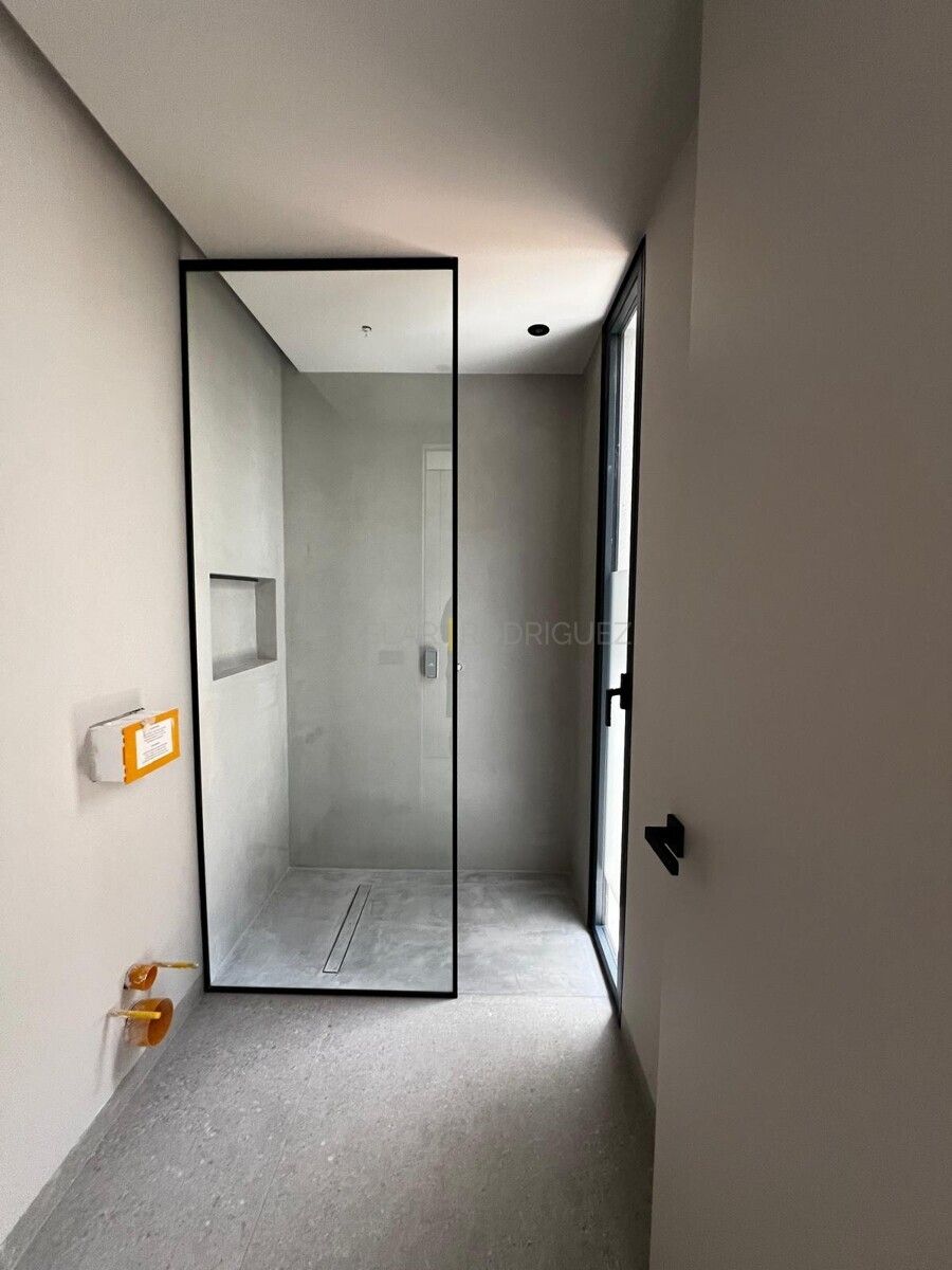 Modernes Badezimmer mit begehbarer Dusche in einer Villa in Adeje auf Teneriffa. Die minimalistische Dusche verfügt über eine schwarze Umrandung und einen bodenebenen Duschbereich.