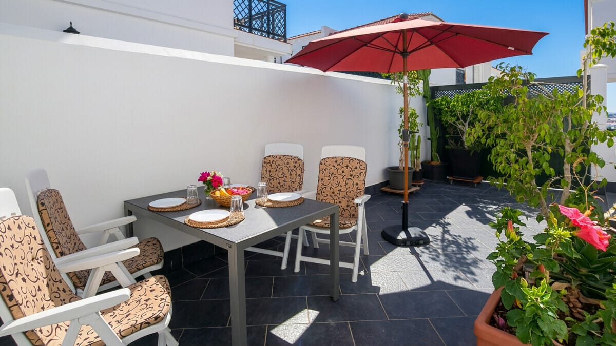 Terrassen-Essbereich für Villa in Abades, Teneriffa, mit Sonnenschirm und Pflanzen.