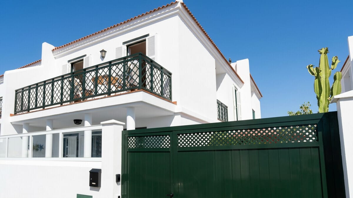 Außenansicht einer weißen Villa in Abades, Teneriffa, mit grünem Tor und Balkon.
