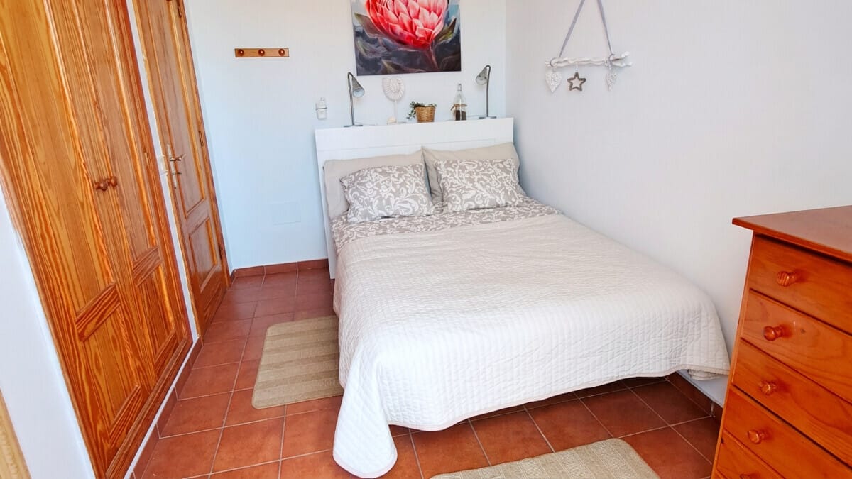 Gemütliches Schlafzimmer auf Teneriffa mit Doppelbett, Holzschrank und Terrakotta-Boden.