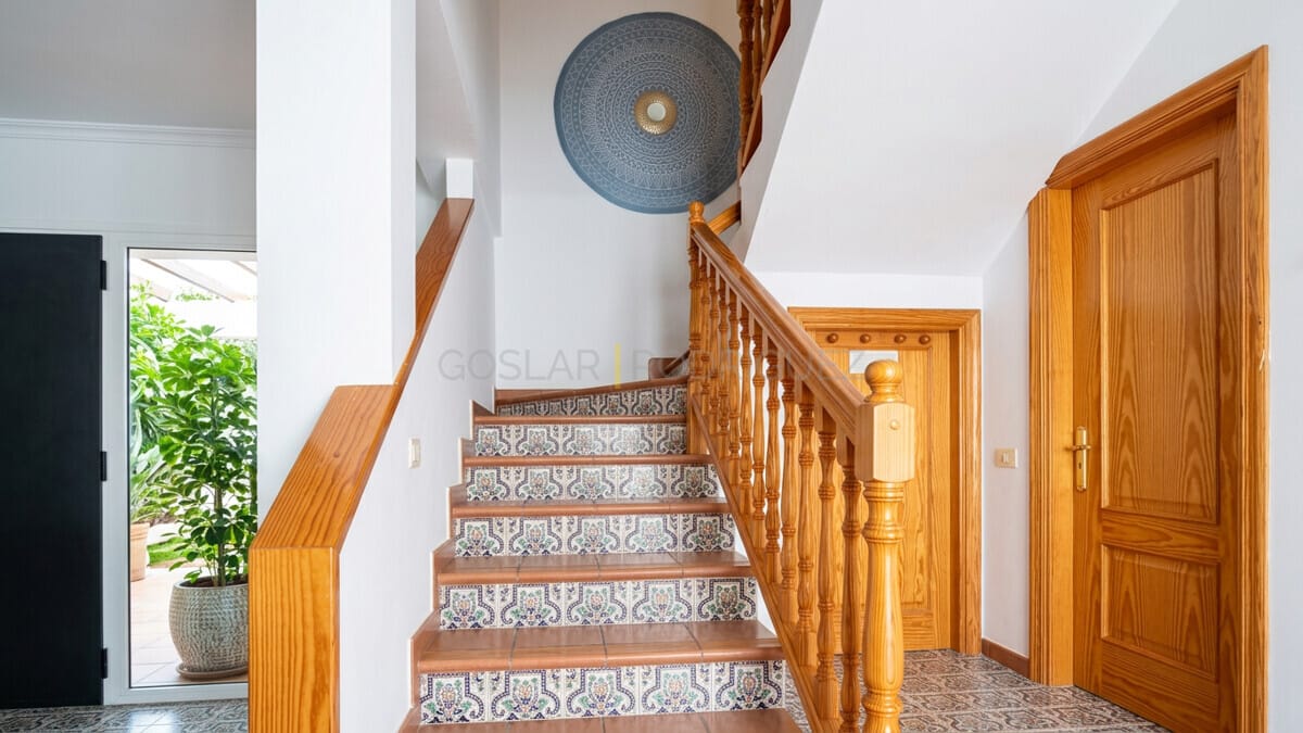 Interior view of a staircase with decorative tiles and wooden railings in a Tenerife villa.