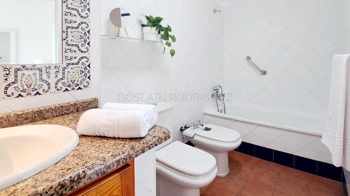 Tenerife bathroom with bathtub, bidet, toilet, and decorative tiled wall.