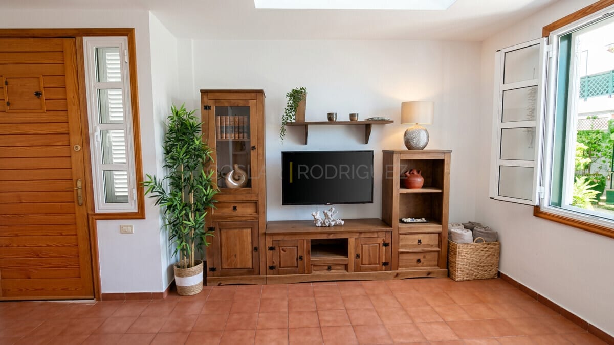 Living room area with wooden furniture, TV, and large windows in a Tenerife villa.