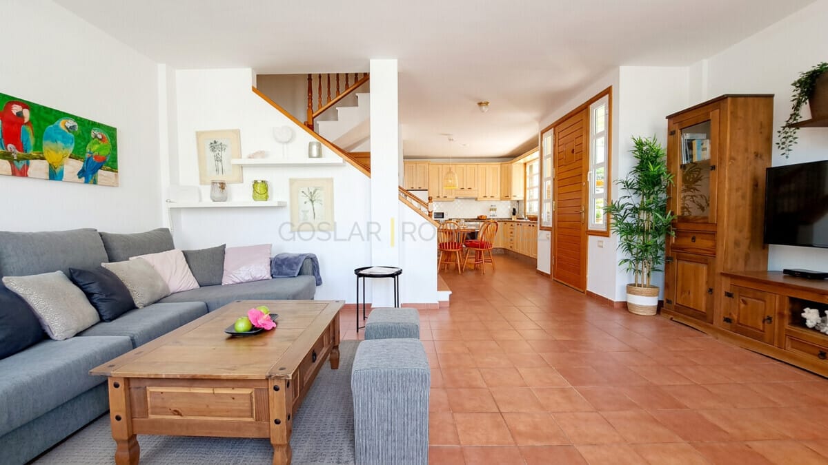 Spacious living room with sofa, coffee table, and open-plan access to kitchen and stairs.