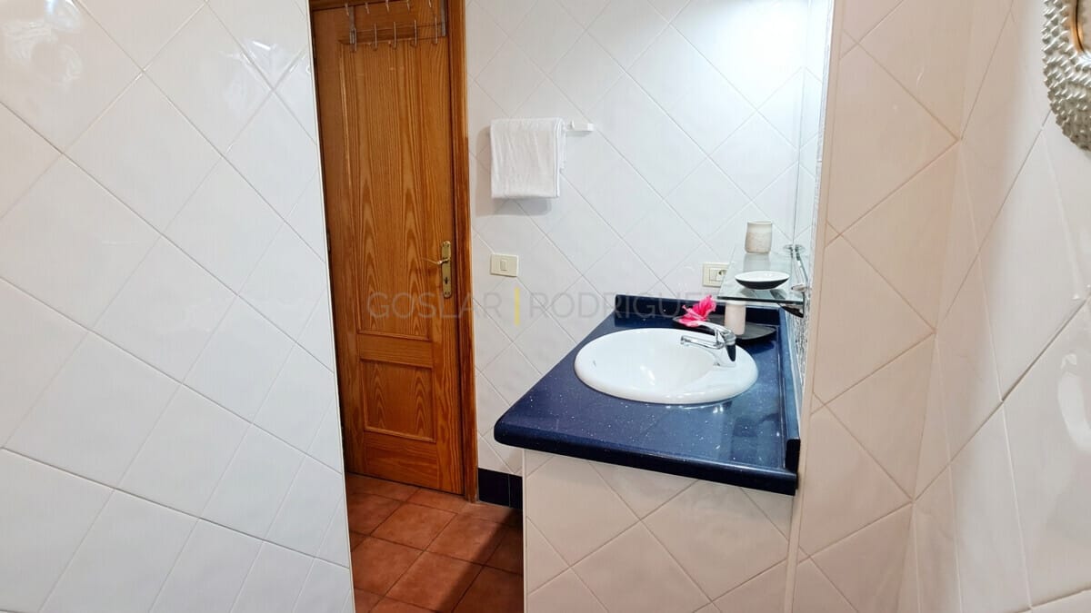 Bathroom vanity with blue countertop, sink, and wooden door in a Tenerife home.